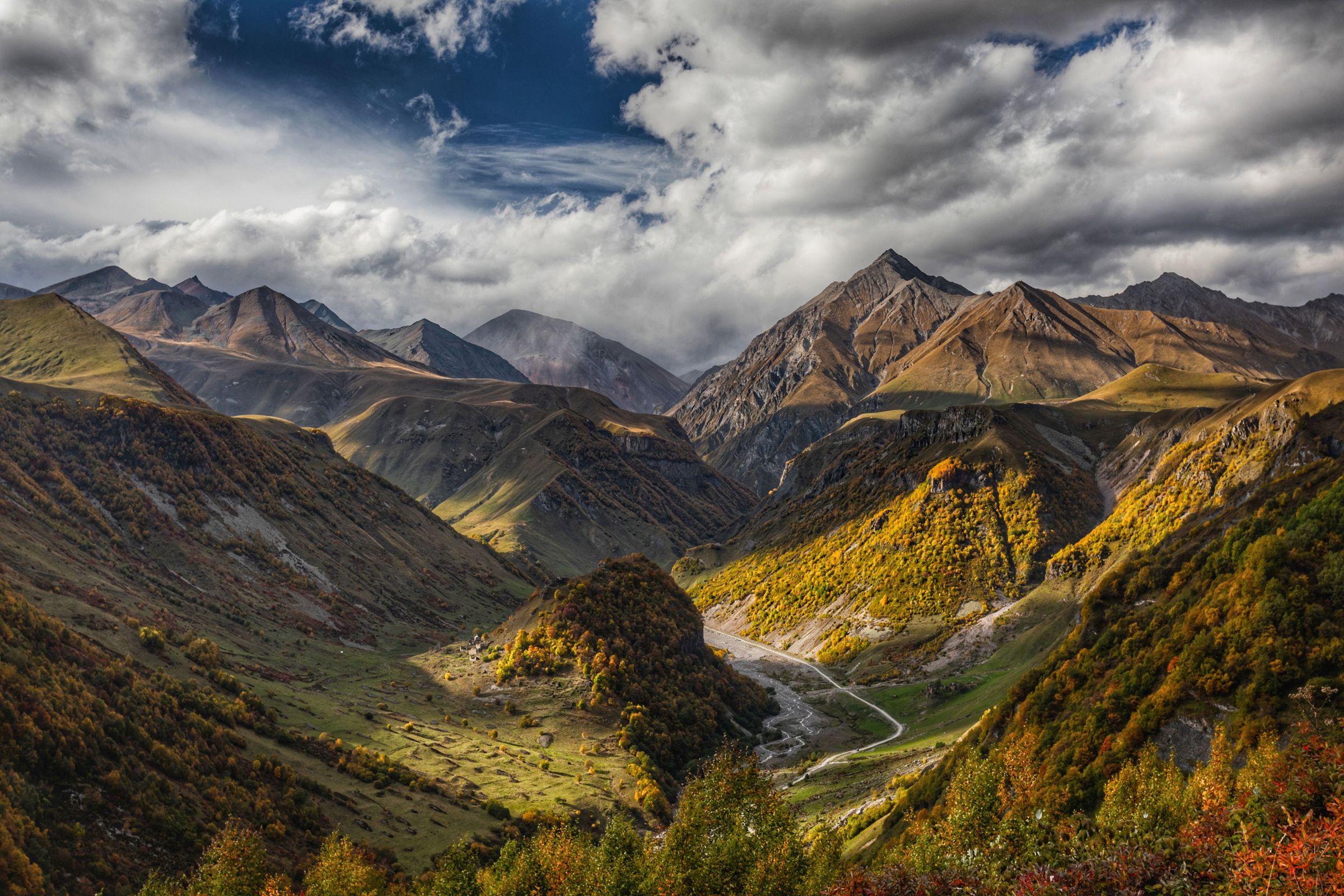 High Caucasus ridge in clear air, rock and residual snow, no road visible.