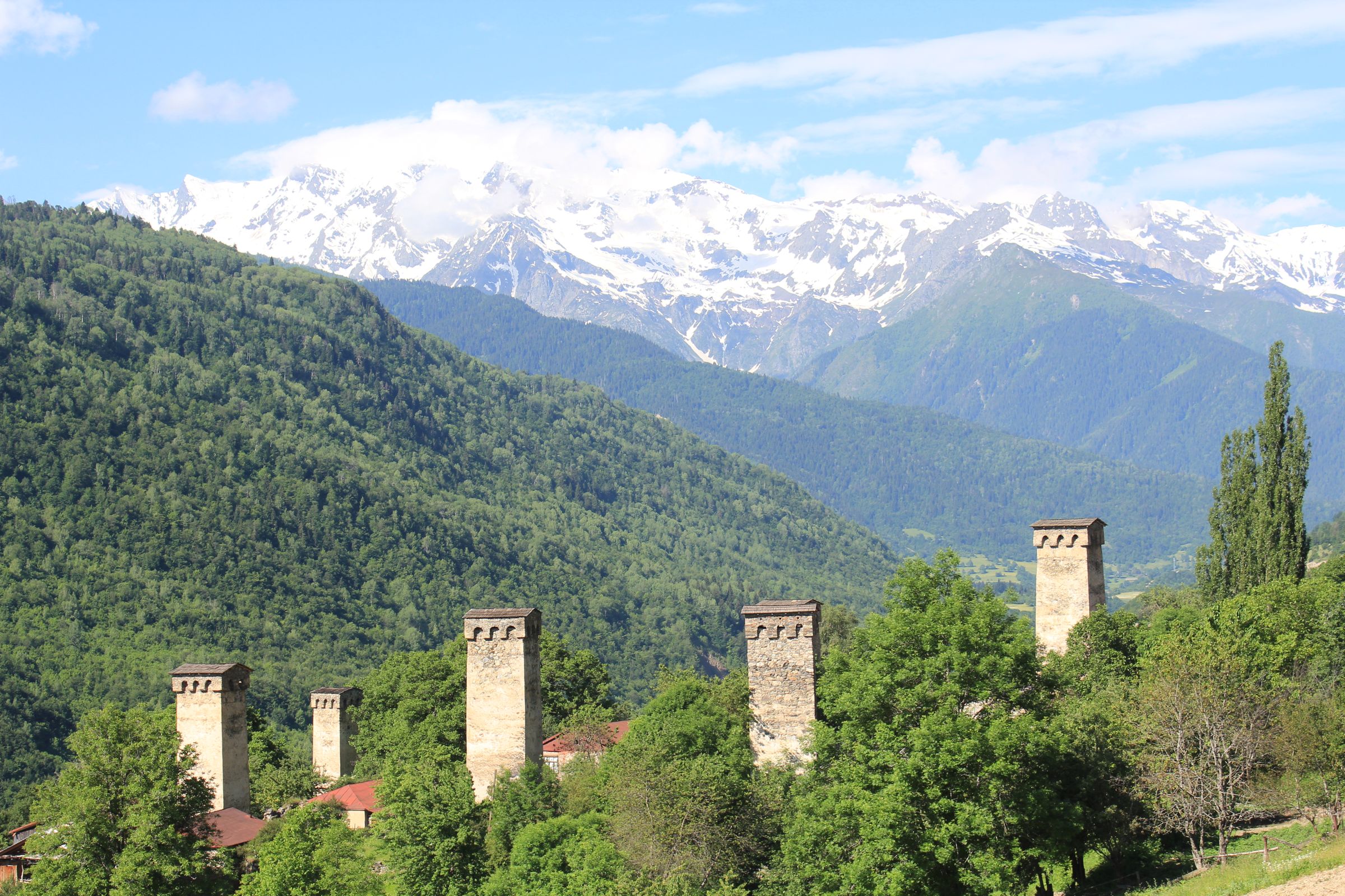 Svan defensive towers standing in front of the Caucasus wall, village at their feet.