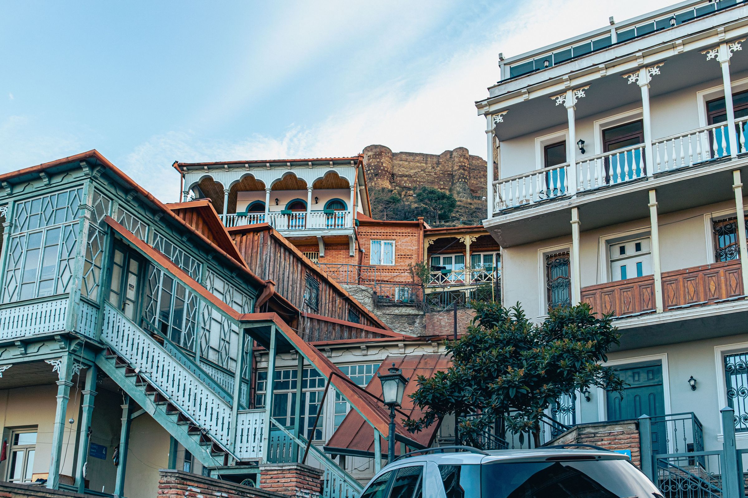 Stacked wooden balconies in Tbilisi Old Town, laundry and grapevine sharing the same ironwork.